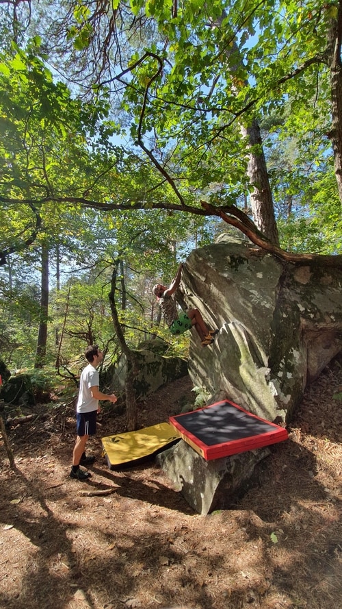 A person bouldering in Mont Ussy, with someone spotting