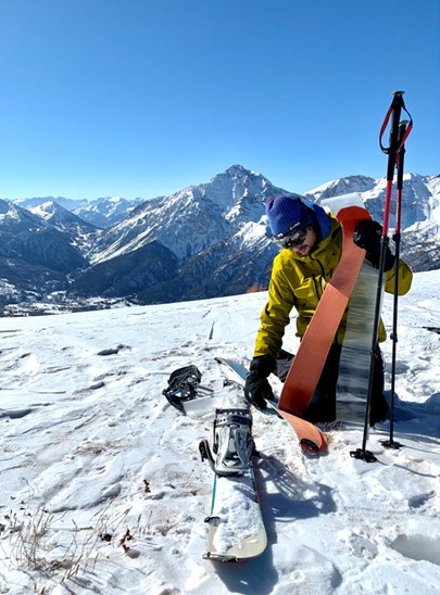 Uno scialpinista che toglie le pelli dei suoi sci