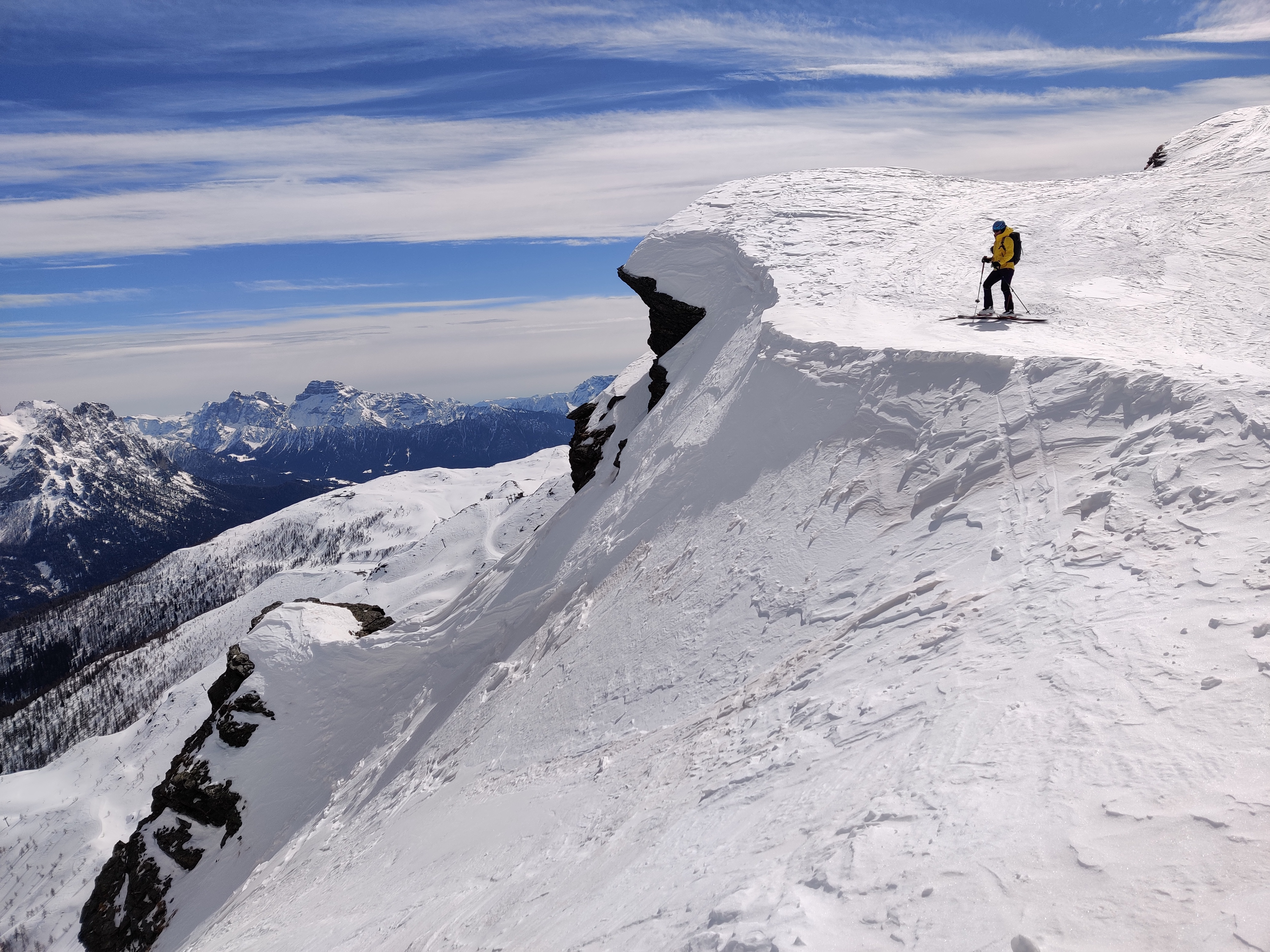 Uno scialpinista in piedi su un altopiano, con vista sulle montagne in lontananza