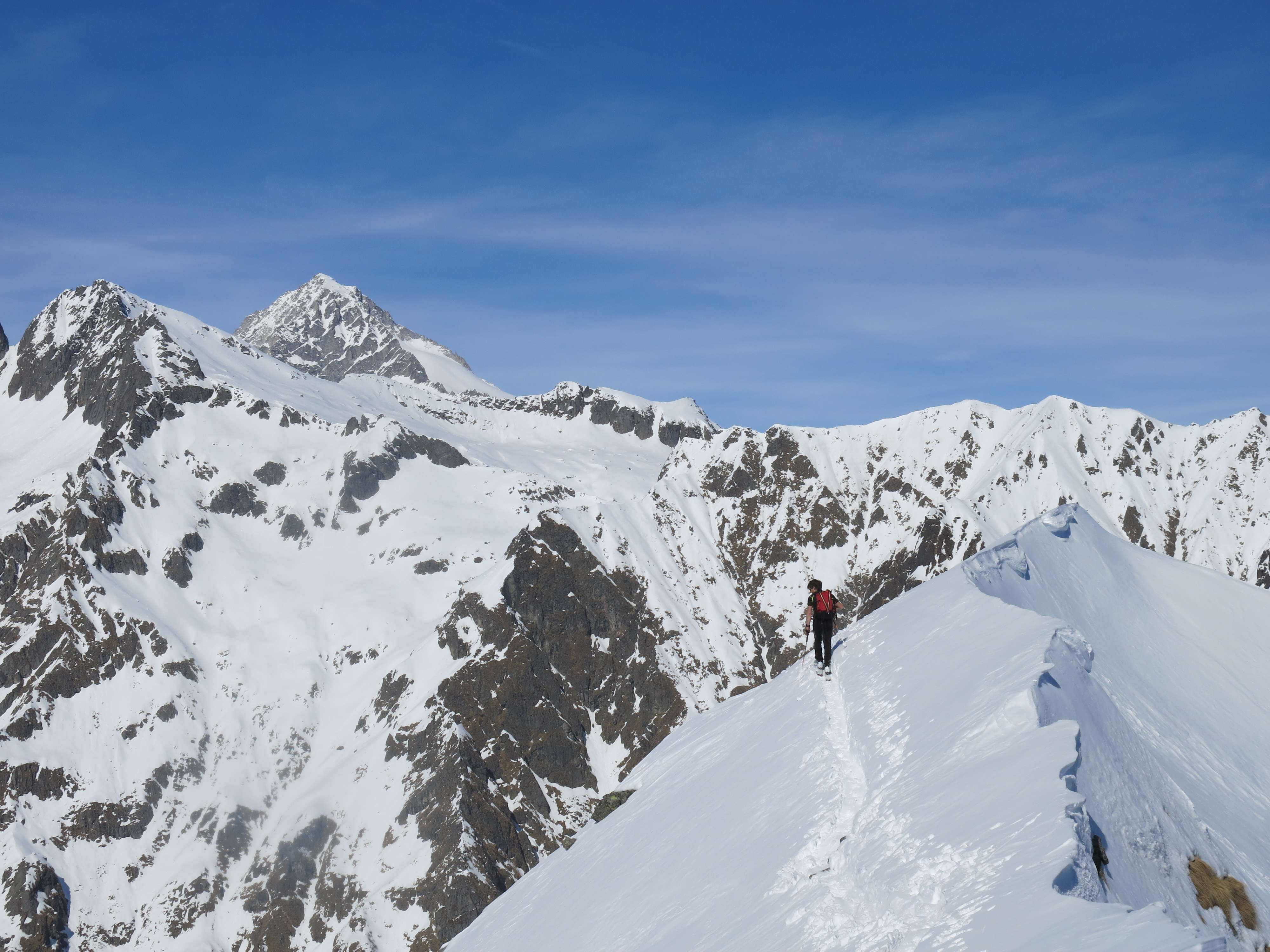 Uno scialpinista che attraversa una cresta con le montagne sullo sfondo