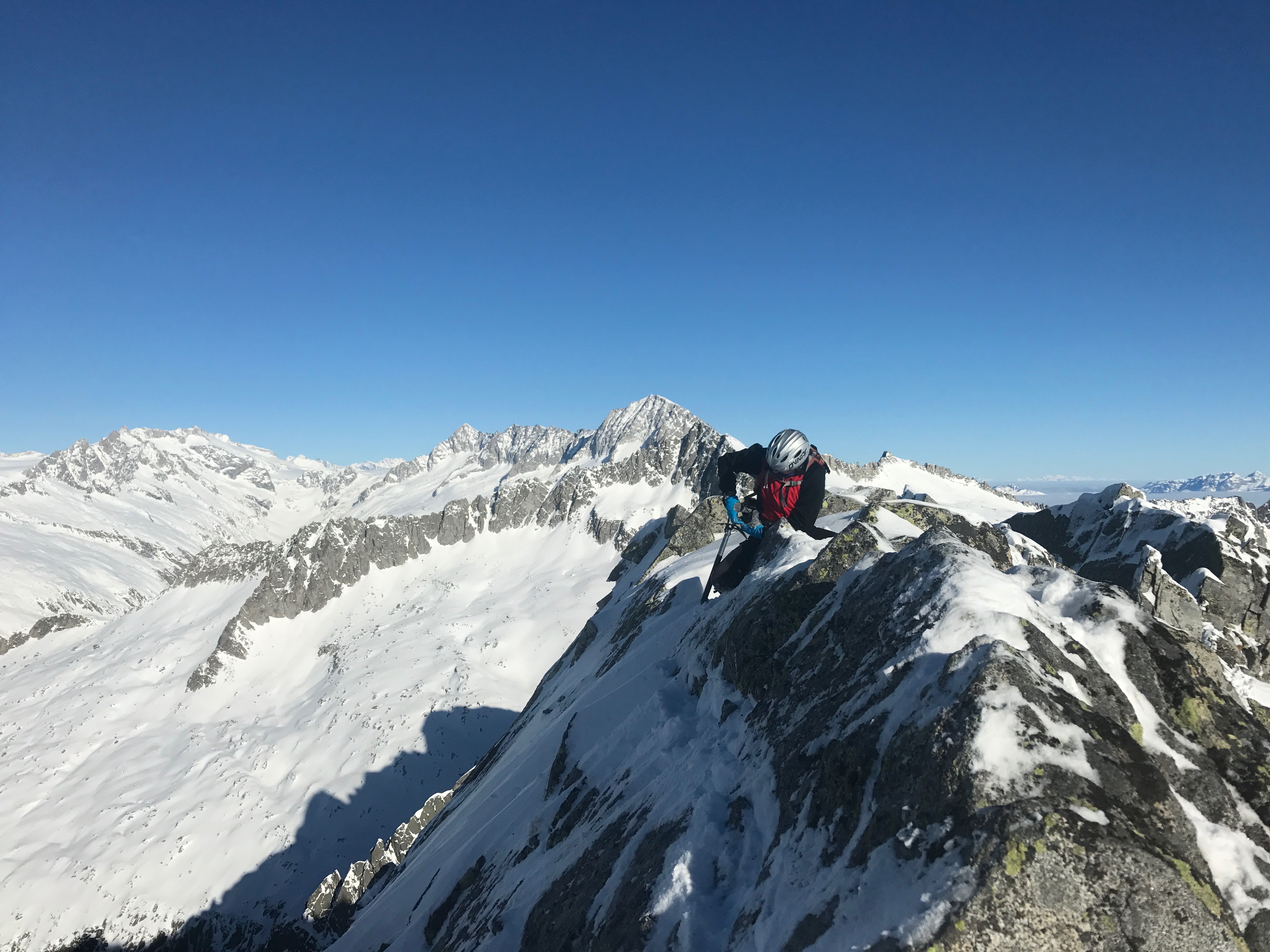 A person ski mountaiineering: climbing a ridge with the snowy mountains in the background