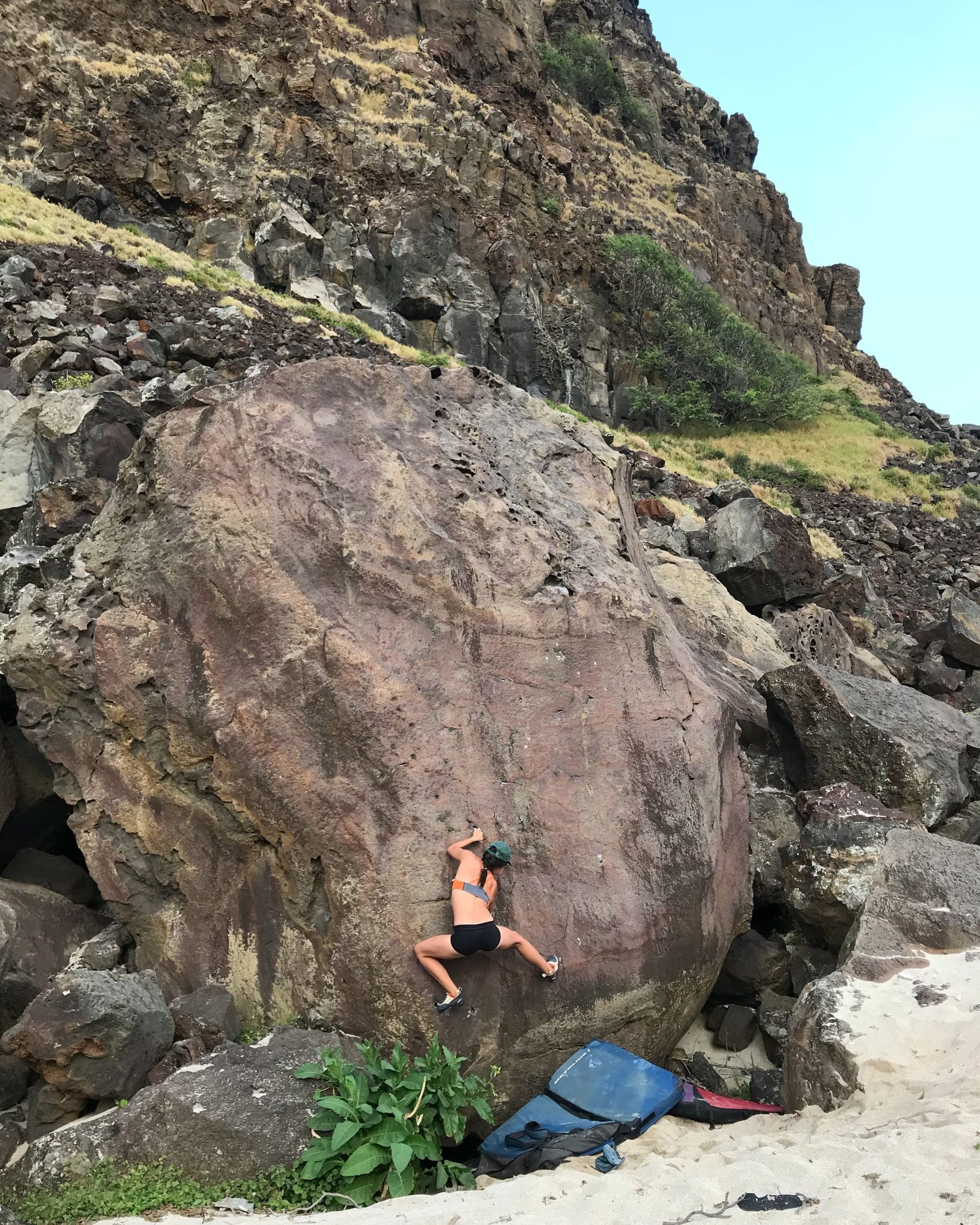 Longshot di una scalatrice su un masso nell'isola di Hawaii