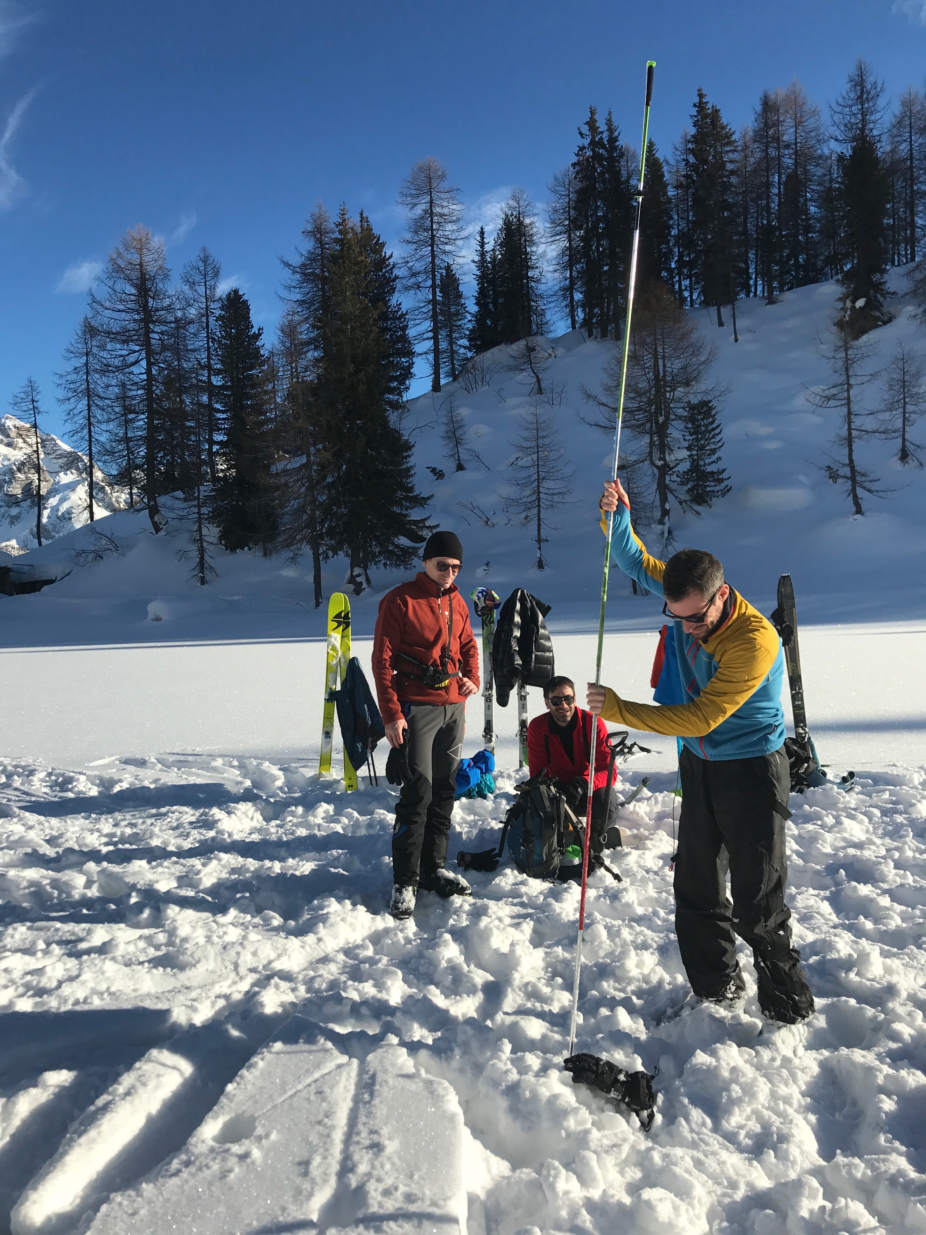 Three tourers using a probe during an avalanche rescue training