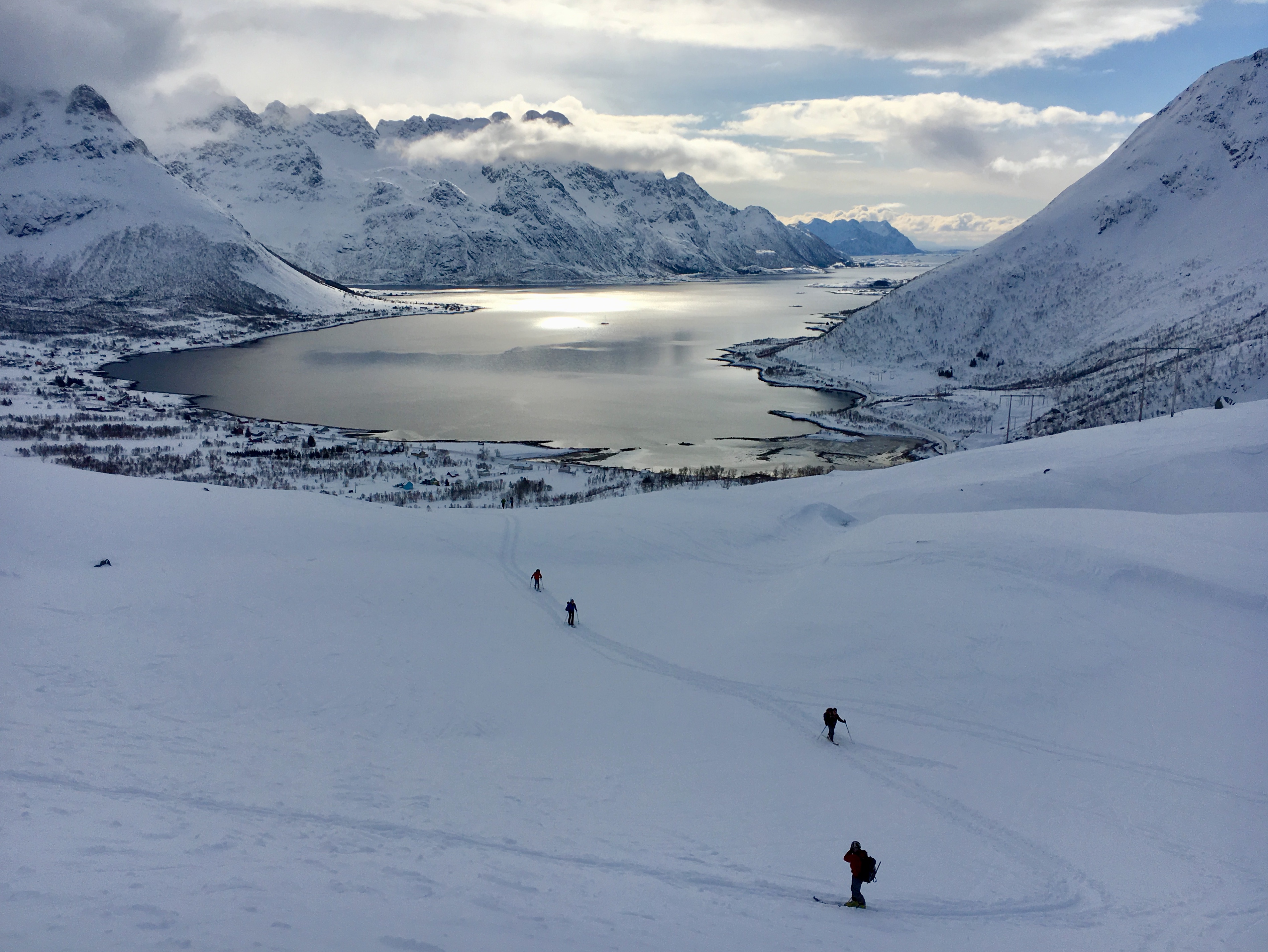 Skiiers ski touring in Lofonten, with the fjord in the background