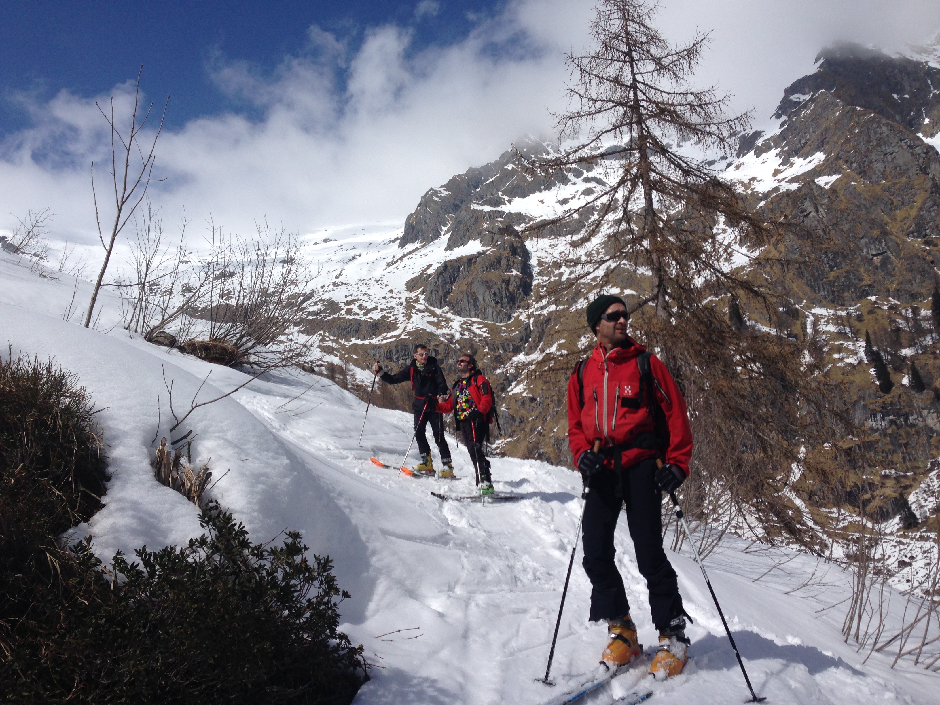 Three people in a valley wearing ski touring equipment