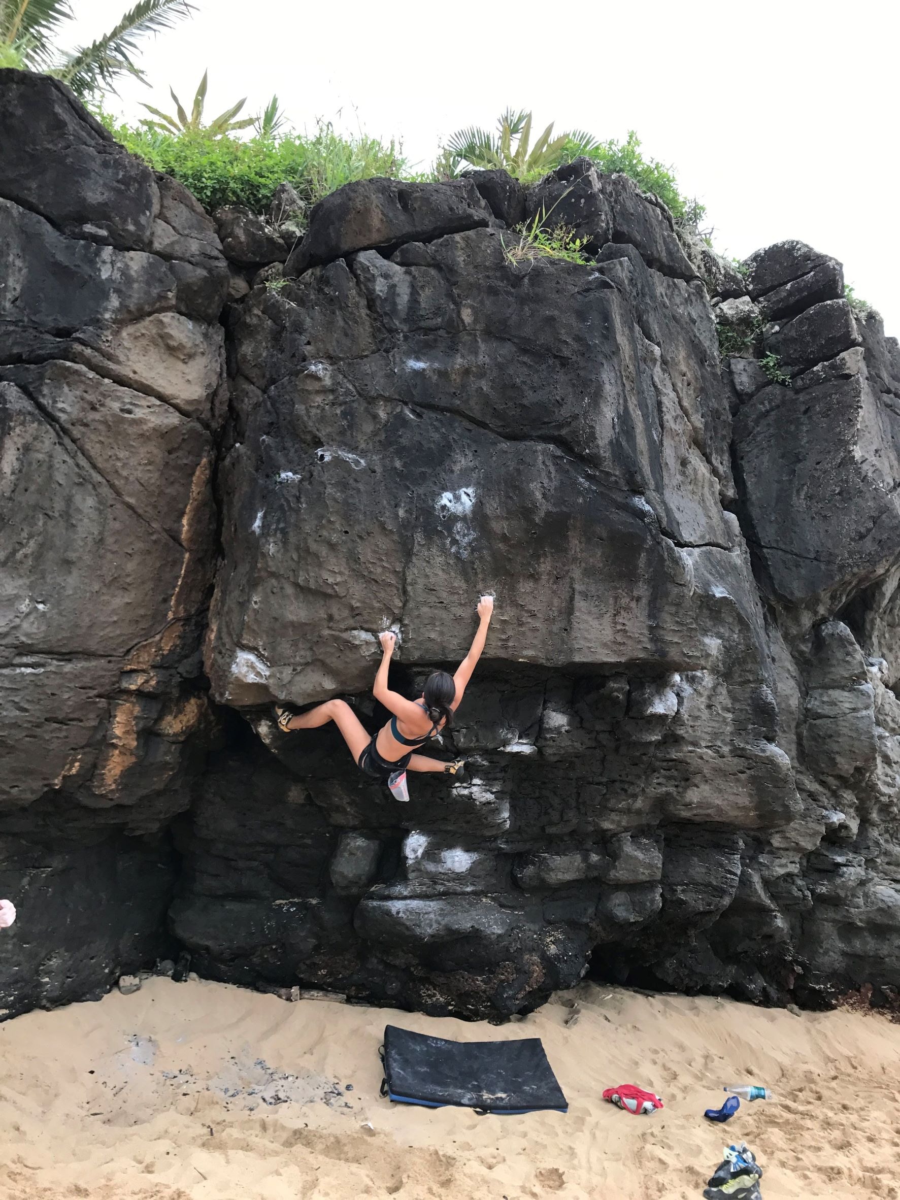 Foto di un arrampicatore sul classico problema boulder T. Rex a Waimea Bay, Hawaii
