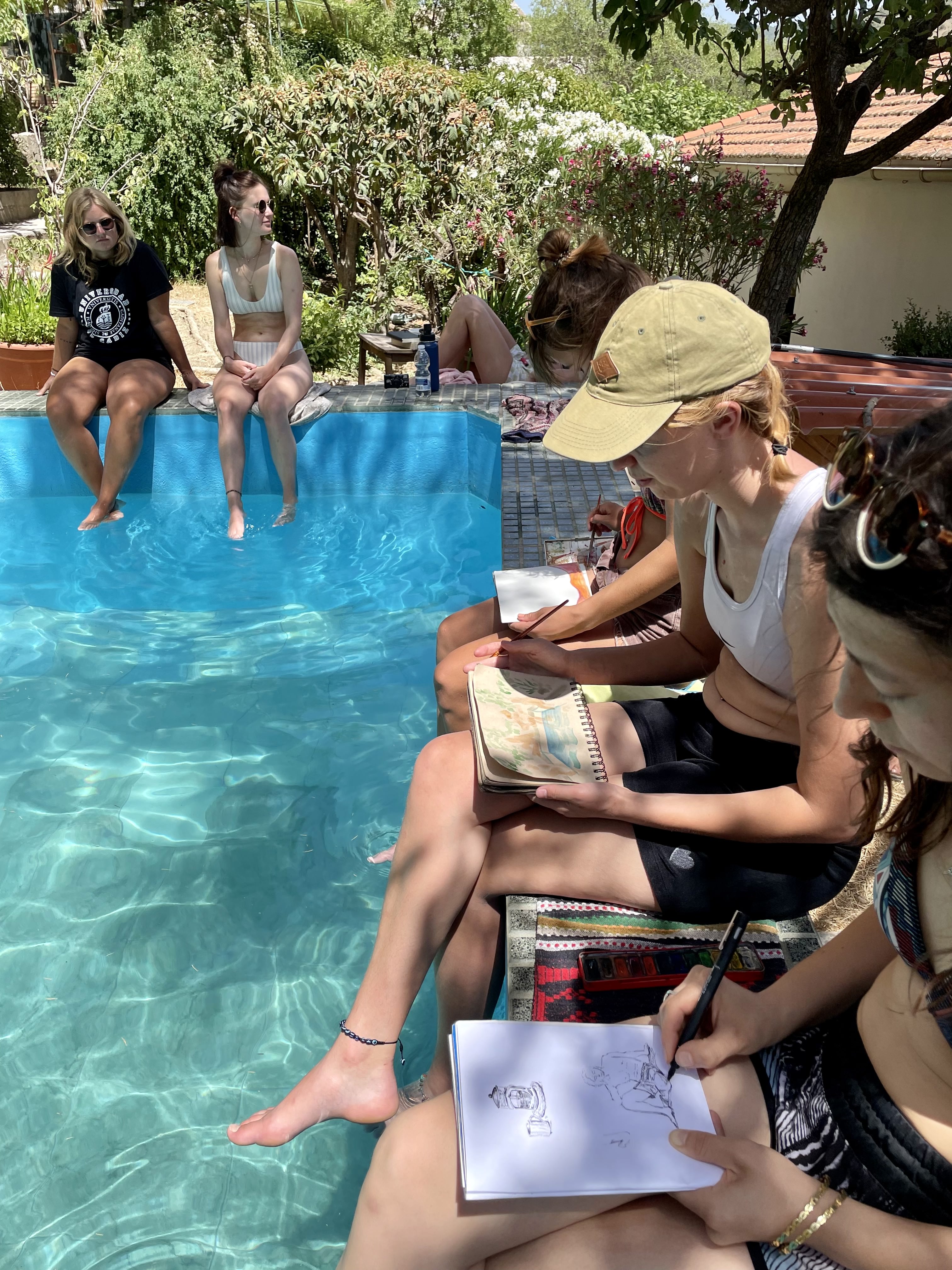 persone sedute intorno alla piscina di Solana de Granada, che disegnano