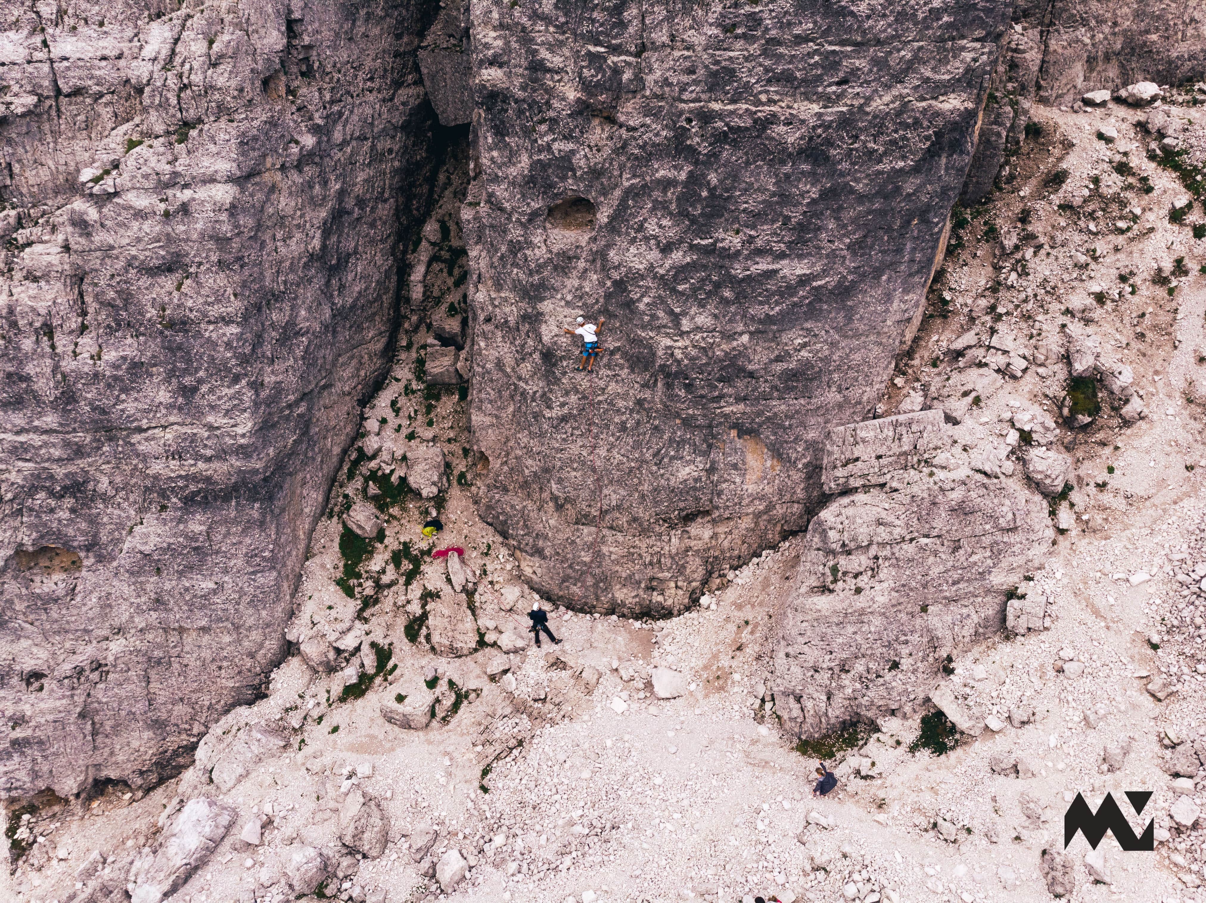A person sport climbing in the Dolomites with another person belaying them