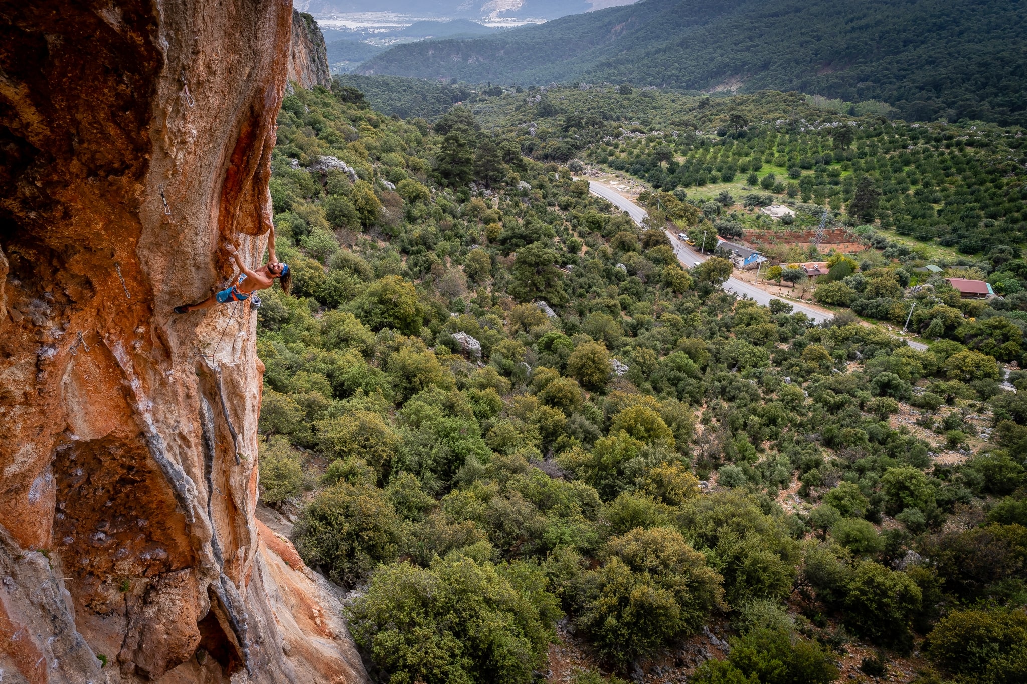 A person rock climbing in Geyikbayiri, Turkey with the valley behind him