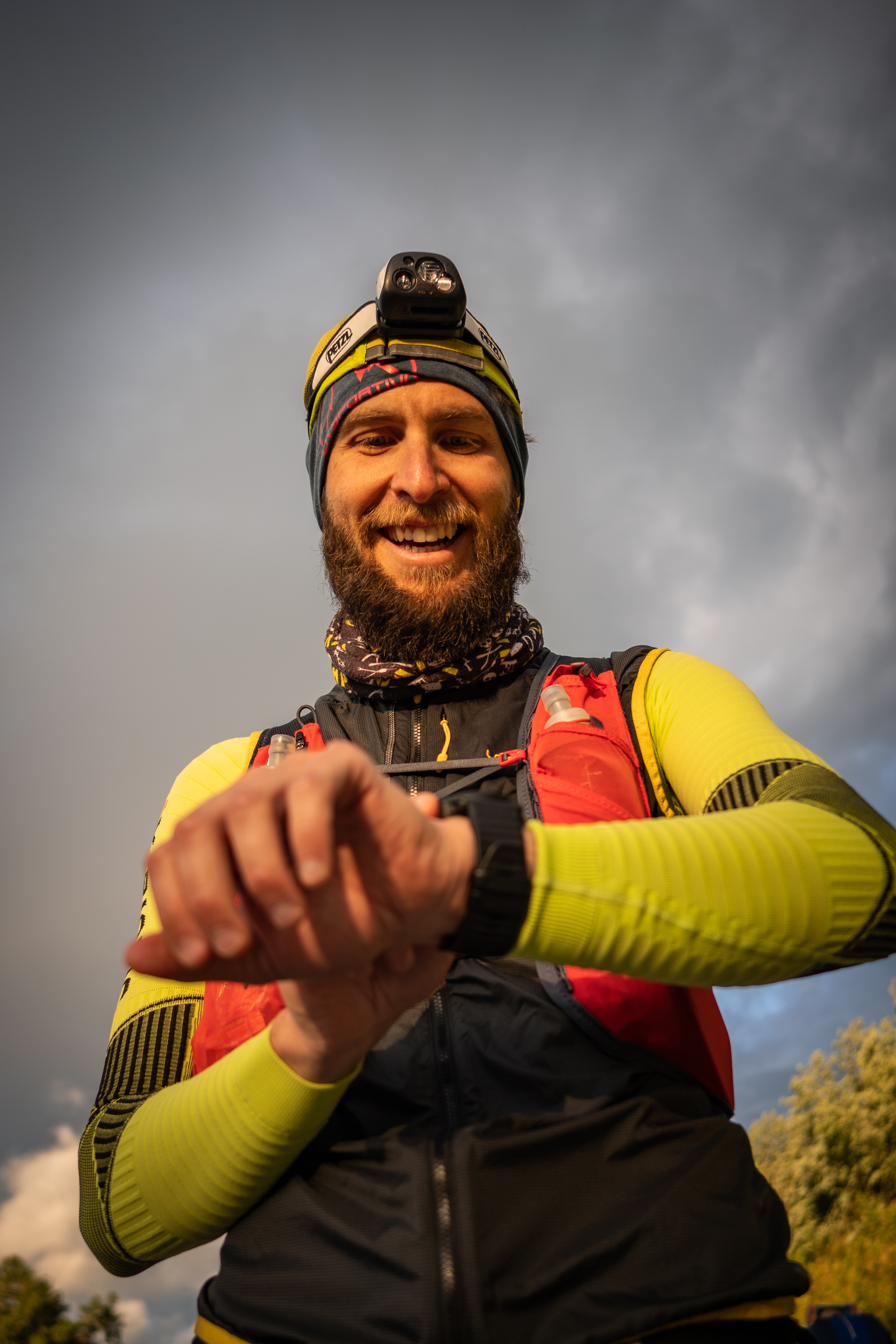 A trail runner smiling and looking at his watch