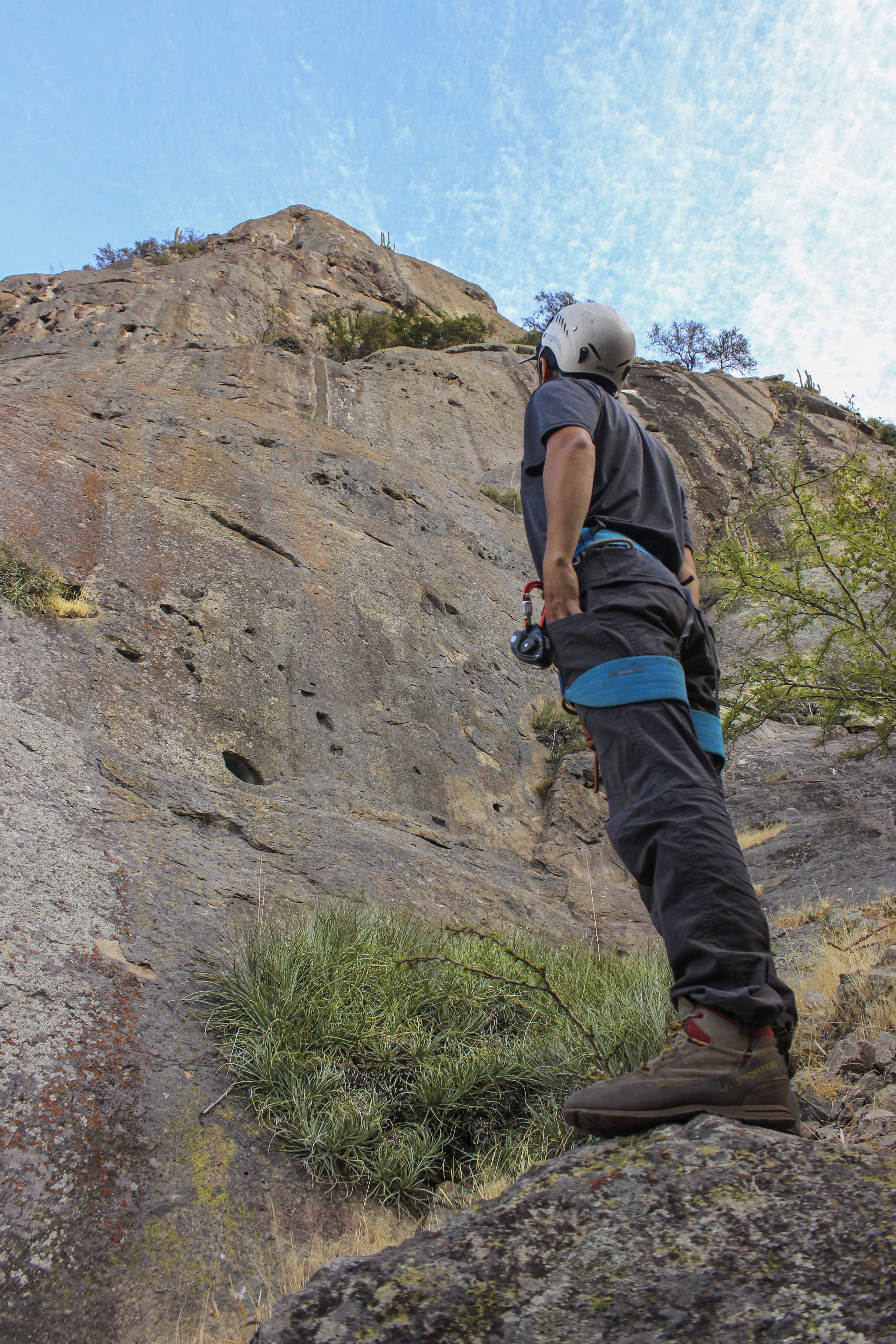 Un arrampicatore con l'imbracatura addosso, guardando una parete rocciosa a La Palmilla, in Cile